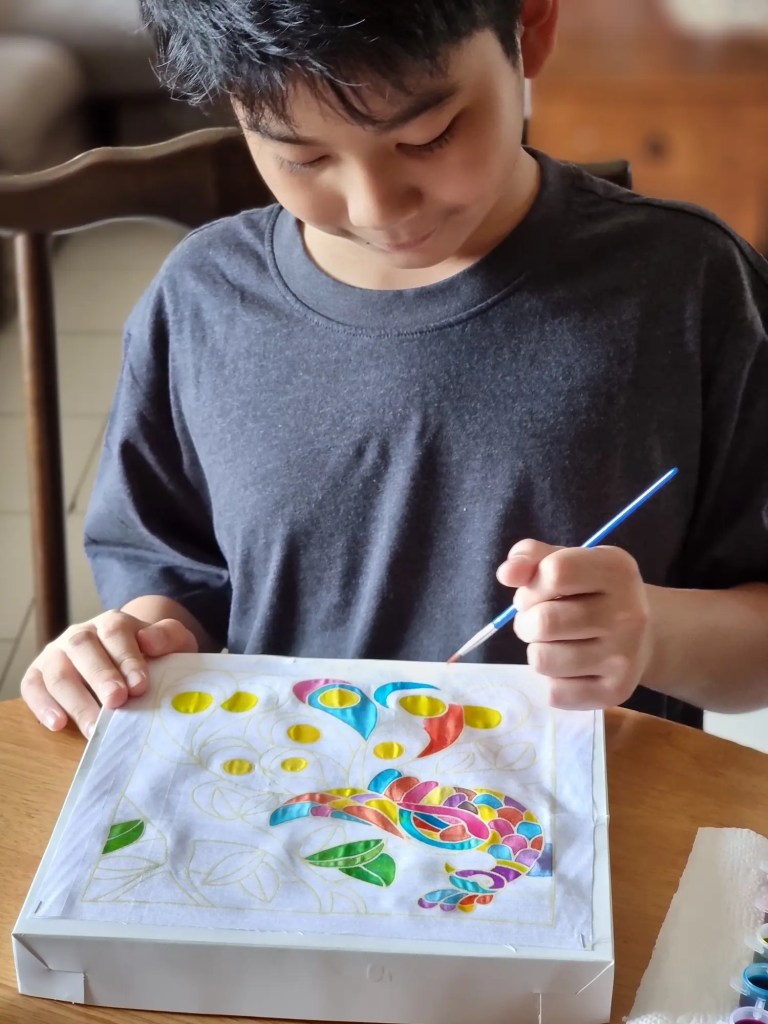 young boy paints colorful design indoors at table 2026 03 19 22 50 22 utc